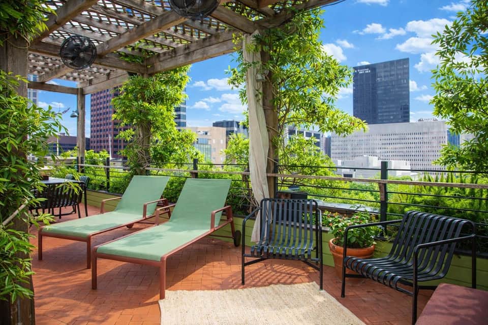 Rooftop terrace with lounge chairs, pergola, and city skyline views