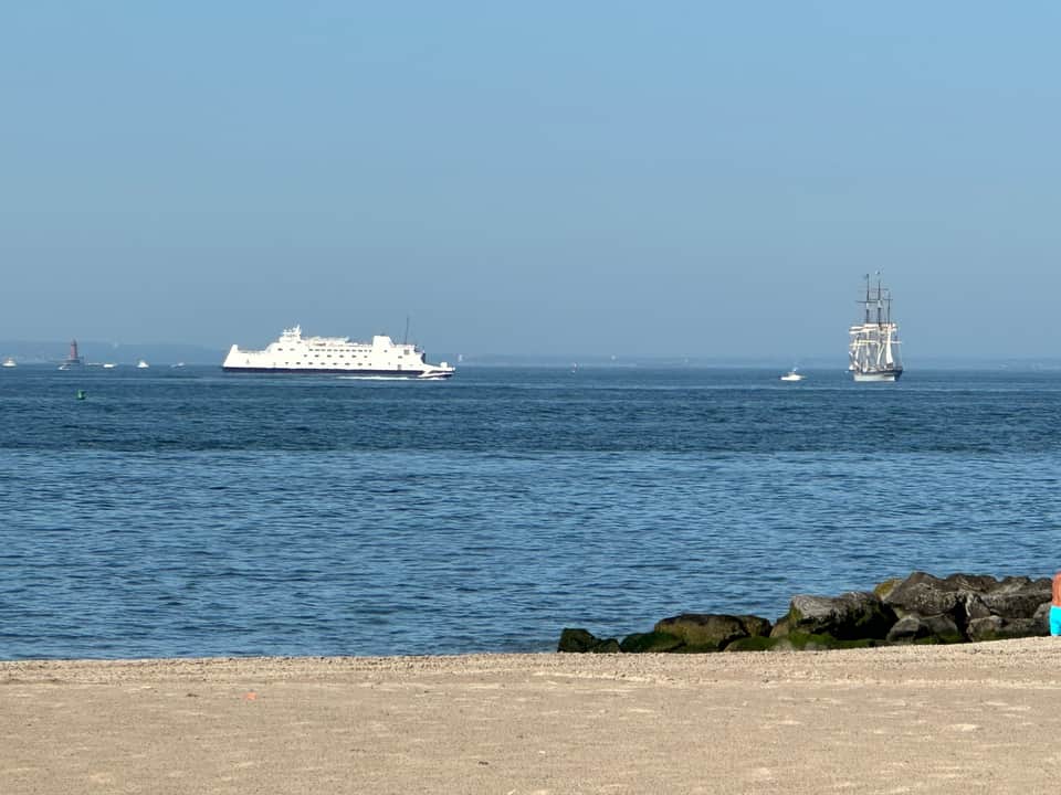 Ocean beach view with cruise ship and tall ship sailboat on horizon