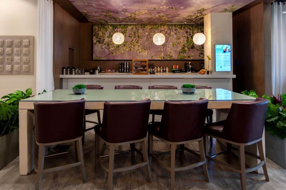 Upscale bar lounge with dark wood elements, botanical ceiling mural, and modern pendant lighting