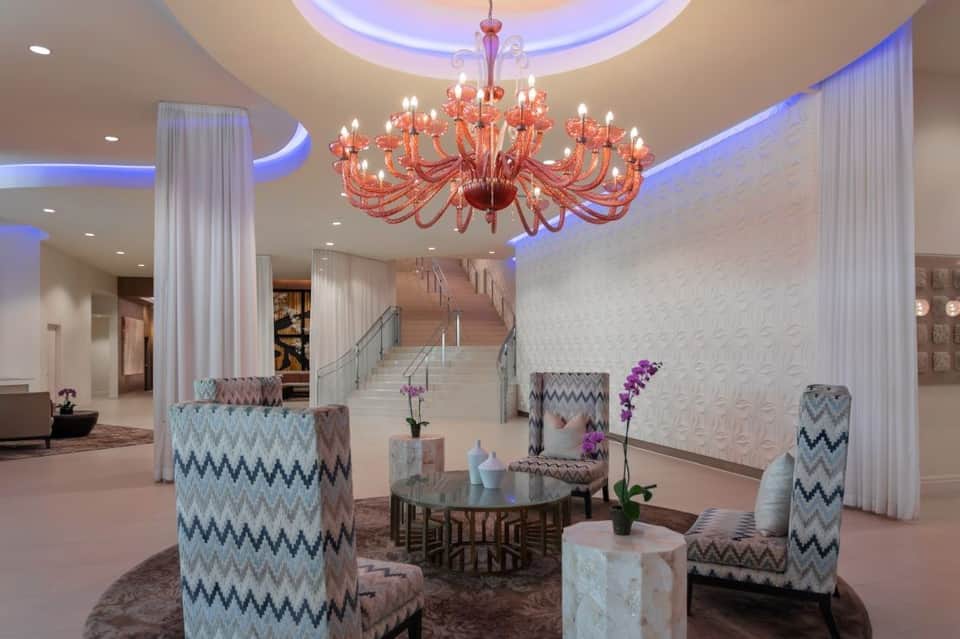 Grand hotel lobby with coral chandelier, soaring ceilings, elegant seating, and marble accents