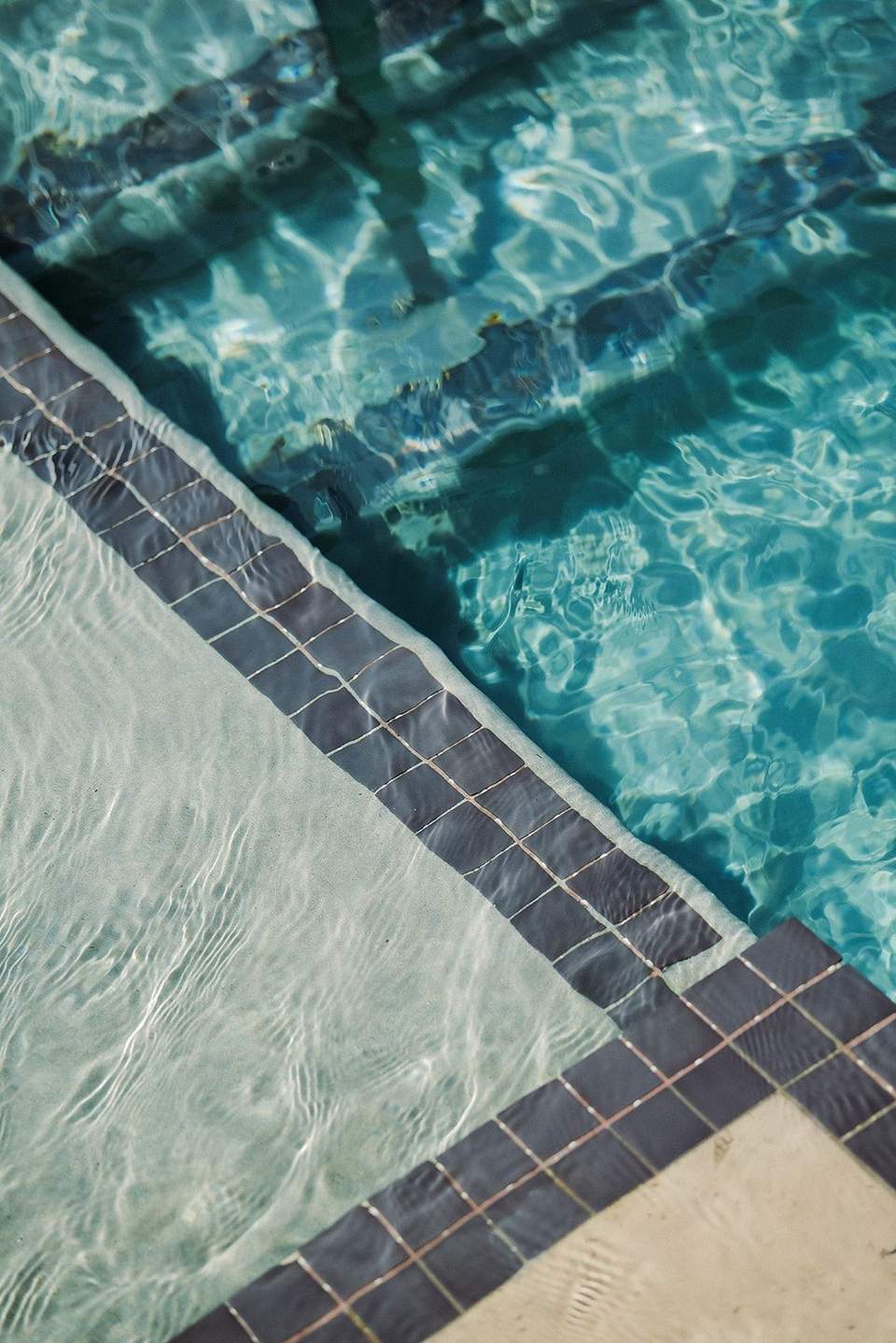Crystal clear pool water with rippling light patterns and tiled edge