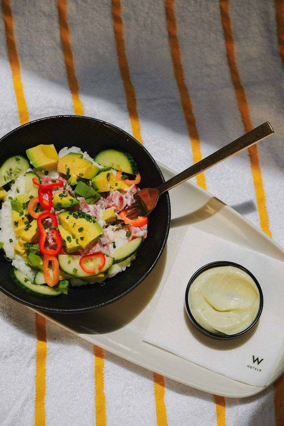 Asian-inspired bowl with rice, vegetables, and protein on striped towel