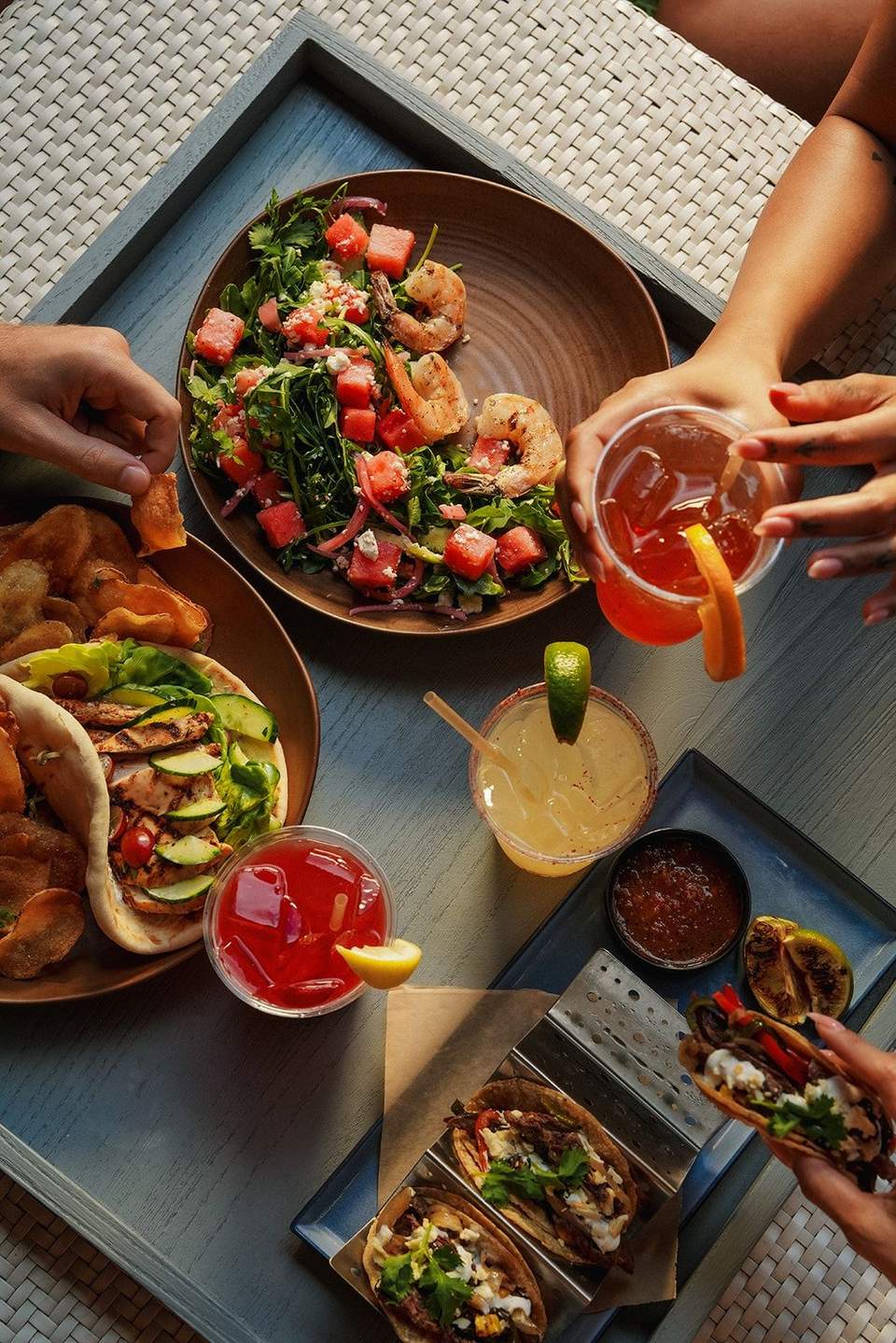 Overhead view of colorful cocktails and seafood dishes being shared