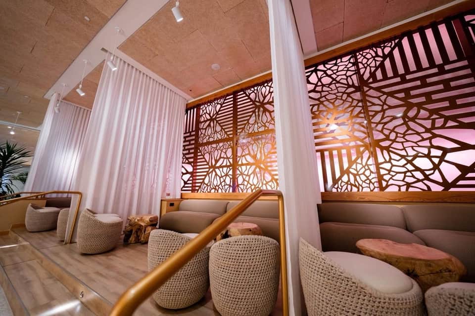 Lounge area with decorative wood screens, pink lighting, and textured seating