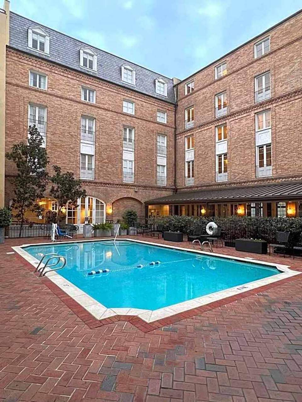 Indoor courtyard pool surrounded by brick buildings with arched windows and ground-level seating