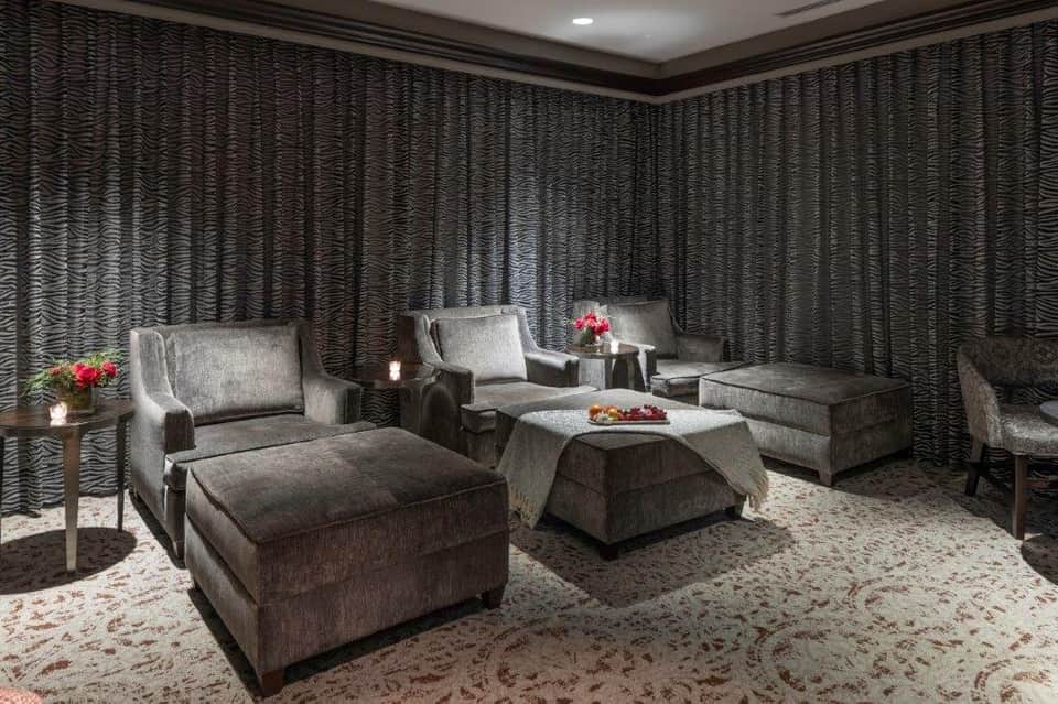 Luxury spa lounge with gray upholstered furniture, textured walls, and soft ambient lighting