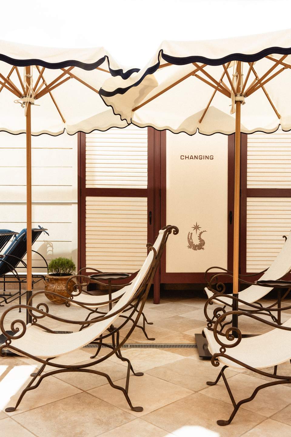 Outdoor cabana lounge area with cream umbrellas, wooden frames, and changing rooms