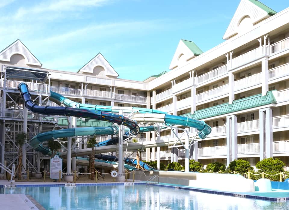 Waterpark with turquoise water slides, pool, and white building with green roof accents