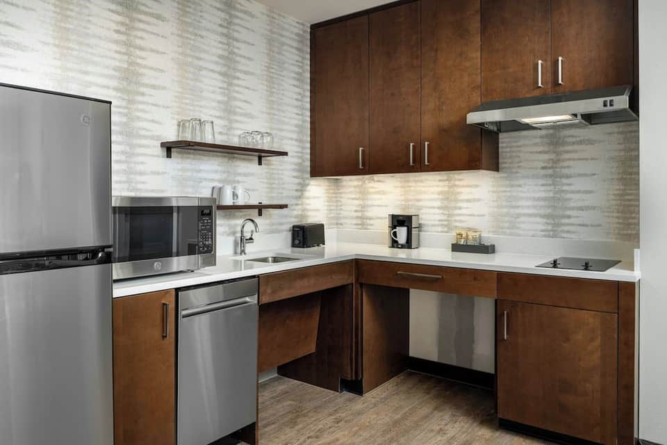 Modern kitchen with wood cabinetry, white countertops, stainless steel appliances, and subway tile backsplash