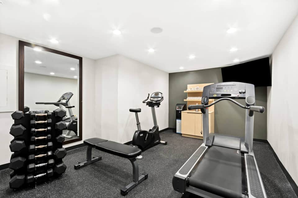 Fitness center with treadmill, stationary bike, dumbbell rack, and mirrored wall