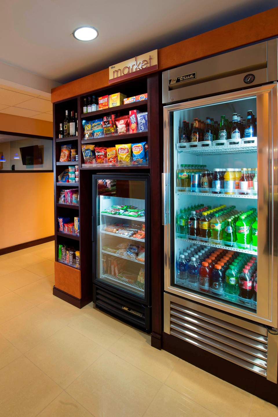 Hotel market convenience station with refrigerated beverage cooler and snack shelving