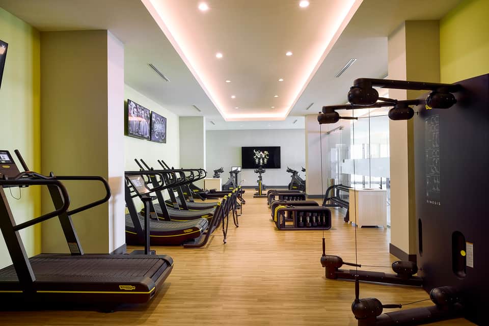 Modern fitness center with yellow accent walls, cardio equipment, and cycling bikes