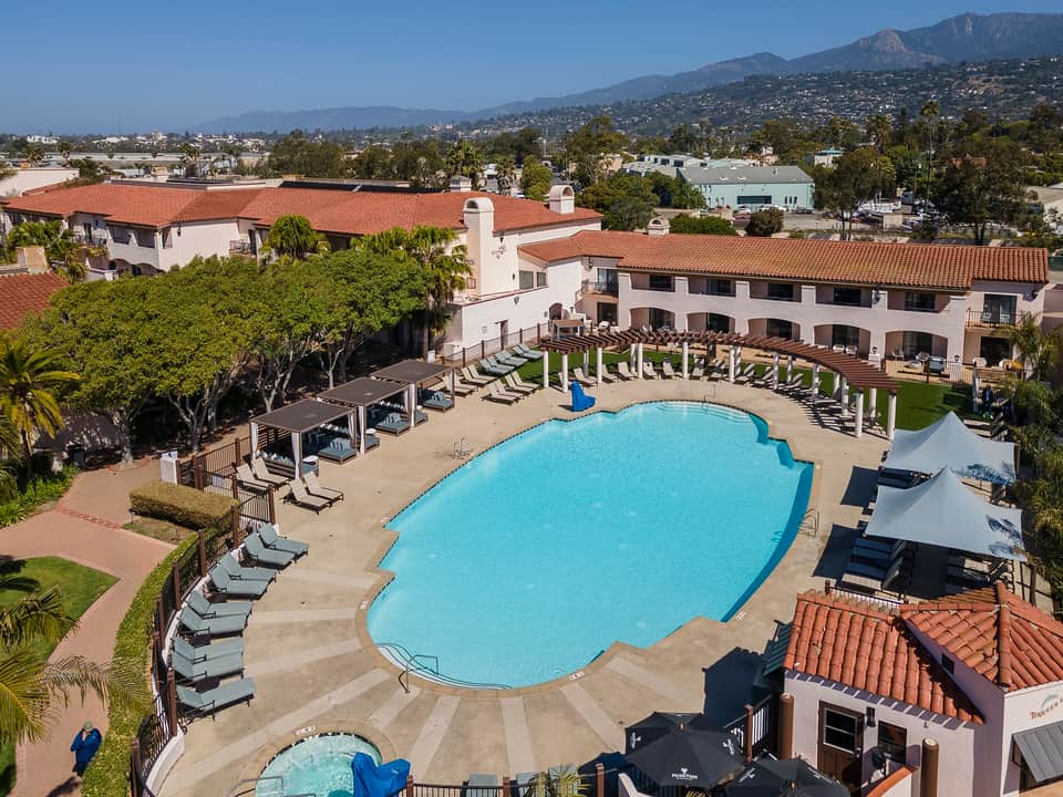 Resort pool area with Spanish-style architecture, palm trees, and mountain views