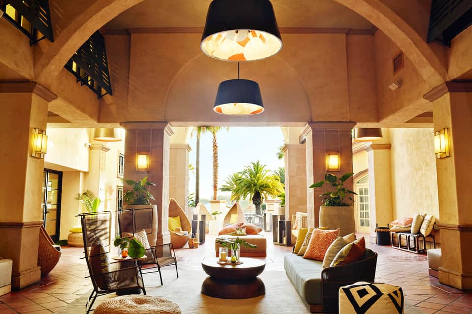 Elegant indoor-outdoor lobby with arched ceilings, hanging pendant lights, and ocean views through columns