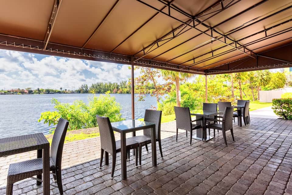 Waterfront dining pavilion with black chairs and tables overlooking a calm lake