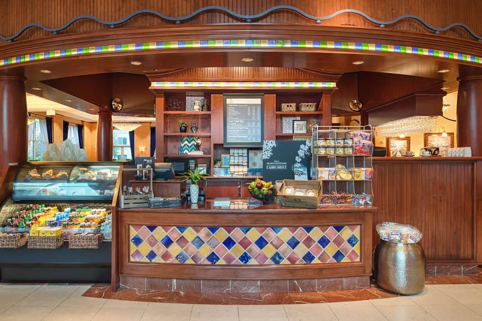 Hotel café counter with colorful mosaic tile work, pastries, beverages, and wooden architectural details