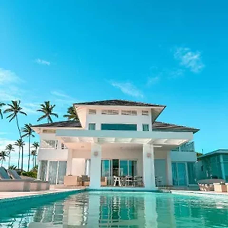 Contemporary white villa with pool, palm trees, and two-story modern architecture
