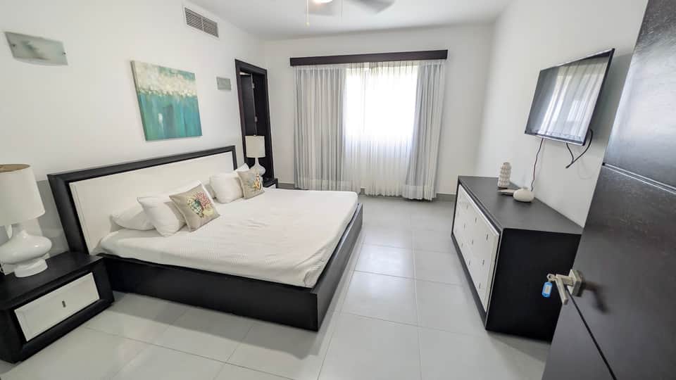 Contemporary bedroom with black and white furnishings, TV, and balcony access