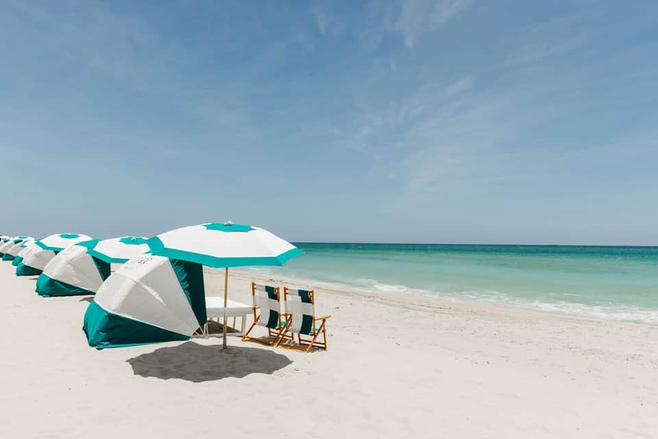 Pristine beach with turquoise umbrellas, lounge chairs, and clear ocean water