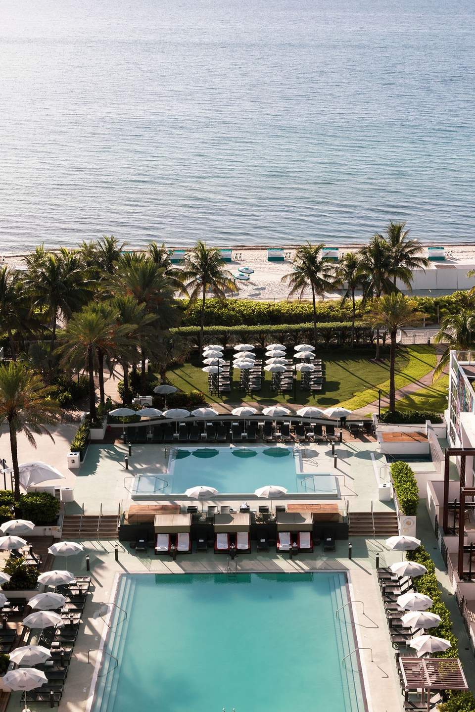 Aerial view of luxury resort with two pools, beach cabanas, and oceanfront property