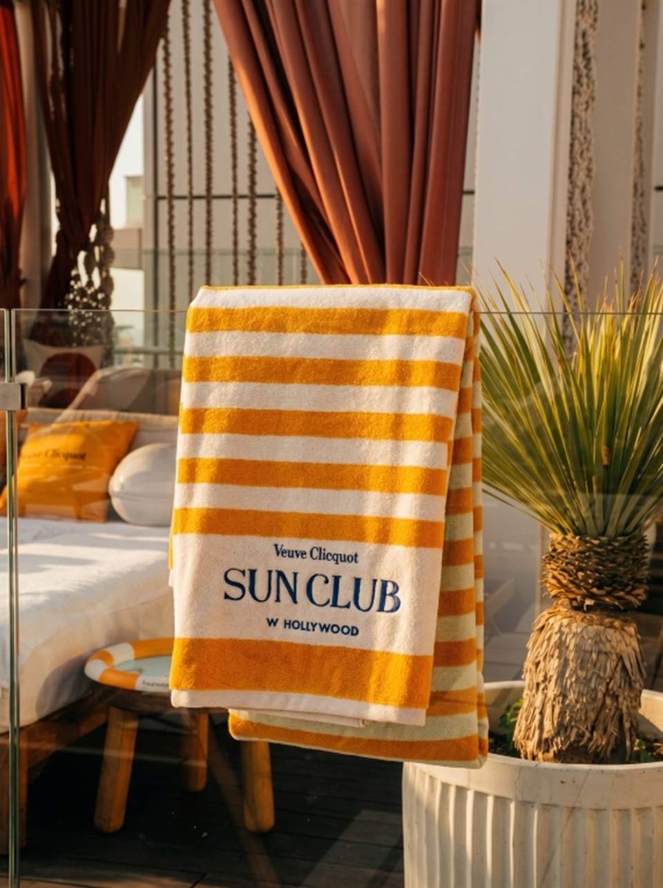 Yellow and white striped beach towel branded 'Veuve Clicquot Sun Club W Hollywood'