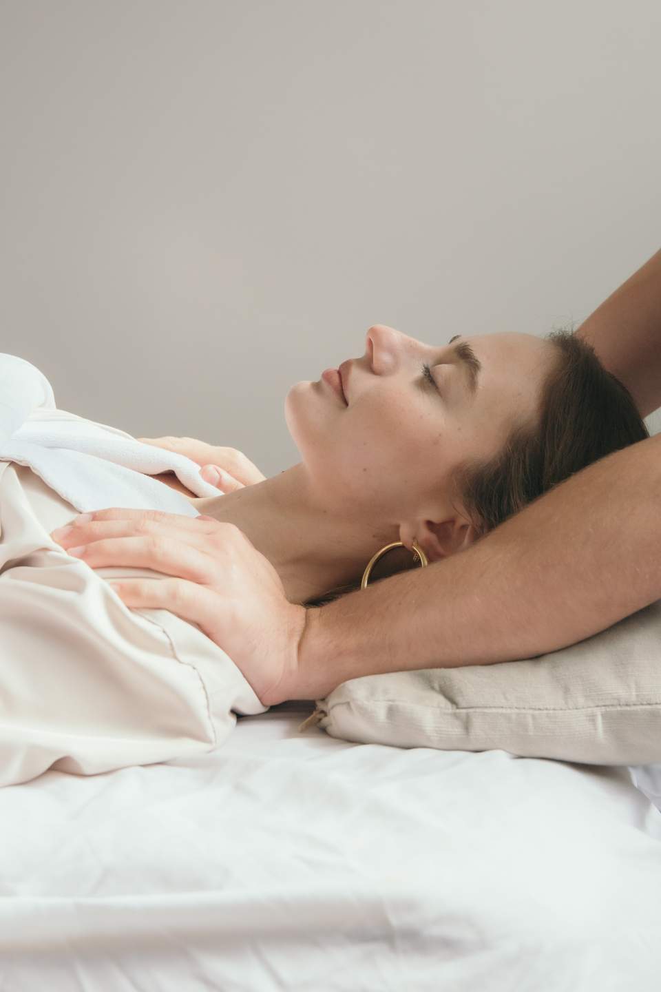 Woman receiving a relaxing head and shoulder massage on a white bed