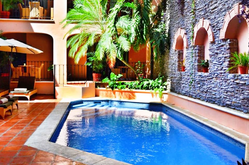 Courtyard pool with terracotta architecture, tropical plants, and stone archways