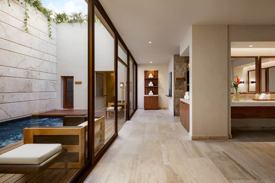 Modern spa hallway connecting indoor hot tub, bathroom, and dressing area with natural wood finishes