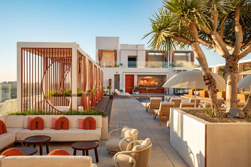 Modern rooftop terrace with lounge seating, architectural screens, and palm trees