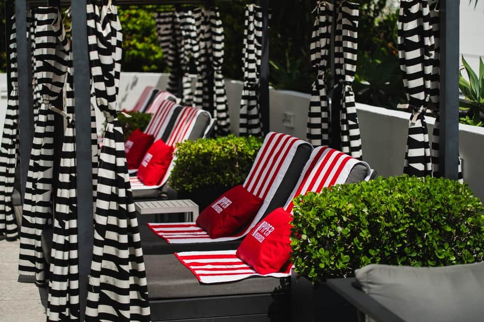 Poolside cabanas with black and white striped curtains and red striped pillows
