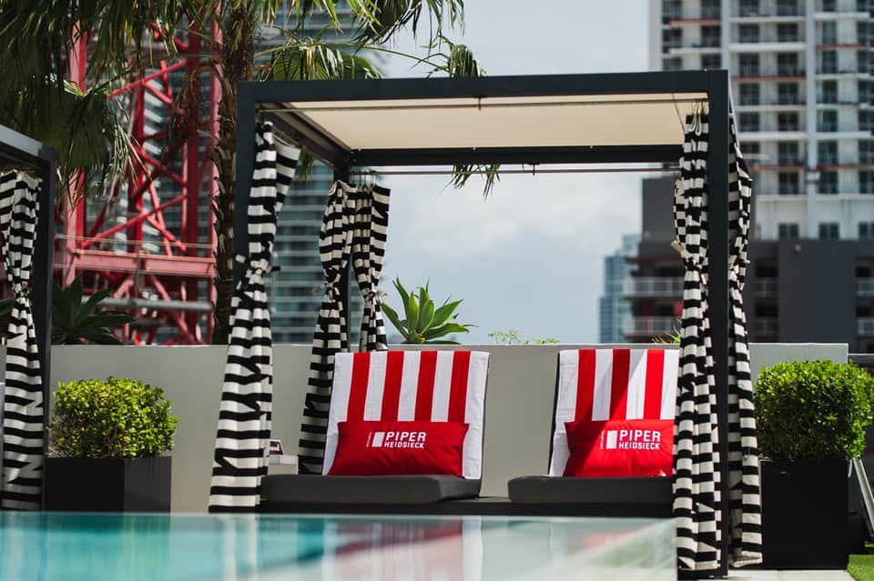 Modern black pergola with striped cabanas and pool reflection in foreground