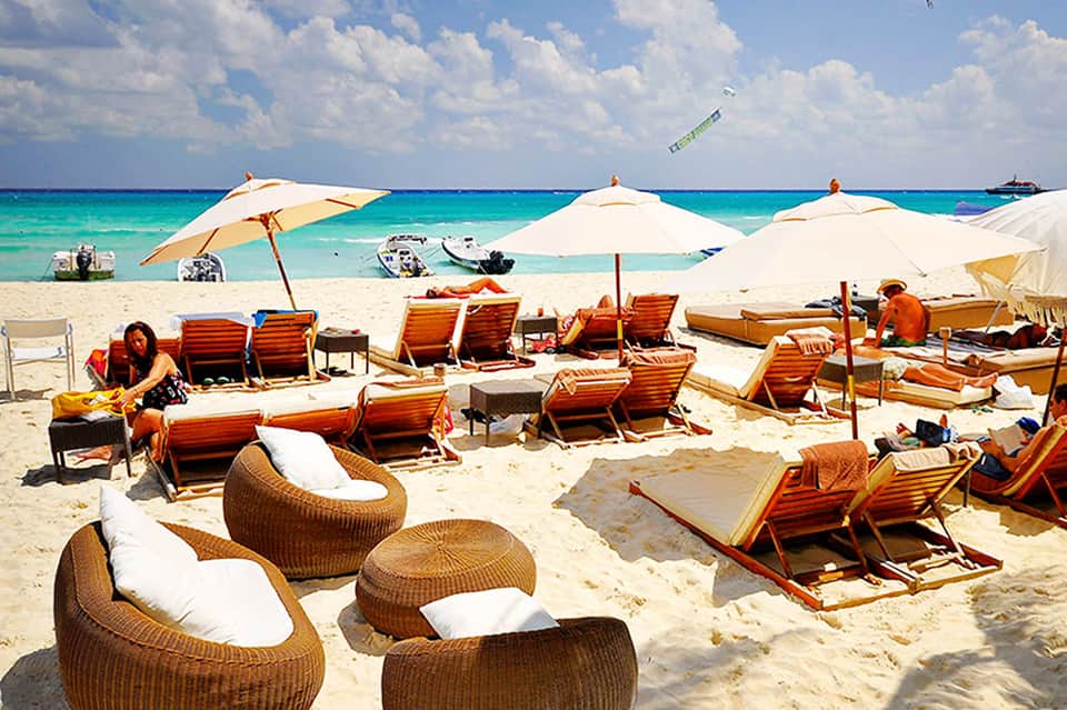 Tropical beach club with lounge chairs, white umbrellas, and turquoise ocean