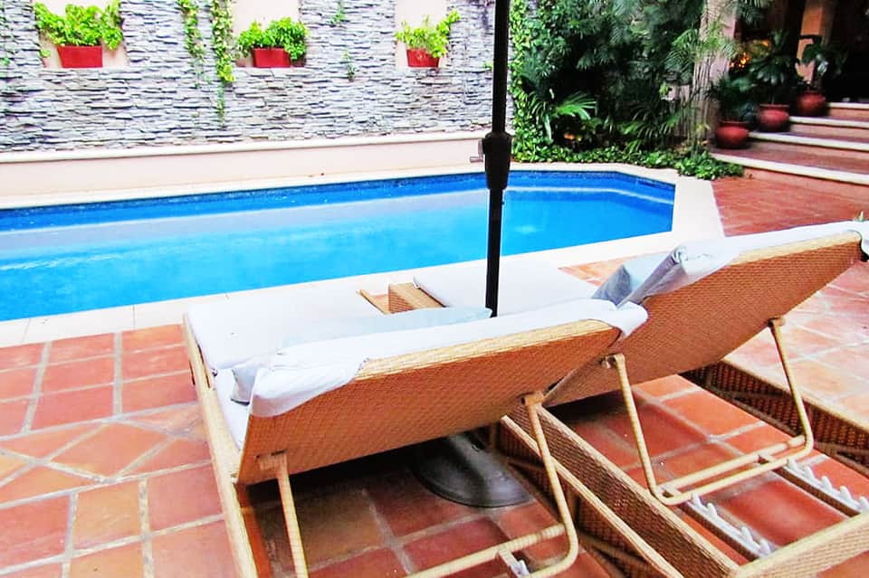 Lounge chairs with umbrella beside blue residential pool