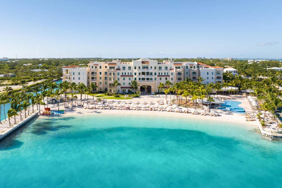 Colorful pastel resort building with beach, lounge chairs, and turquoise water