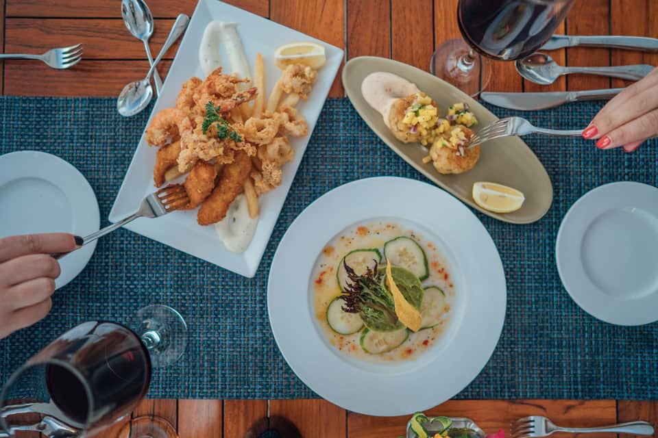 Overhead view of seafood dining with fried shrimp, fish, and appetizers on wooden deck