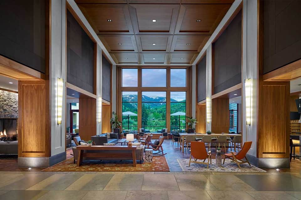 Contemporary lobby with tall windows framing mountain views, wooden pillars, lounge seating, and recessed lighting