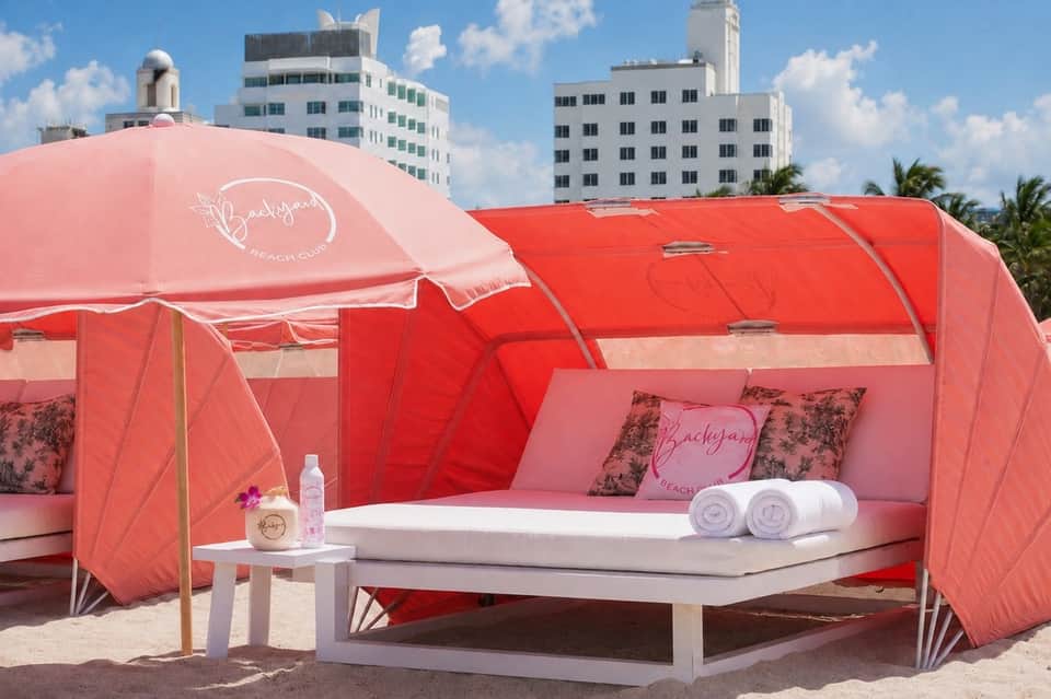 Pink and red glamping pod with bedding and amenities on Miami beach with city skyline