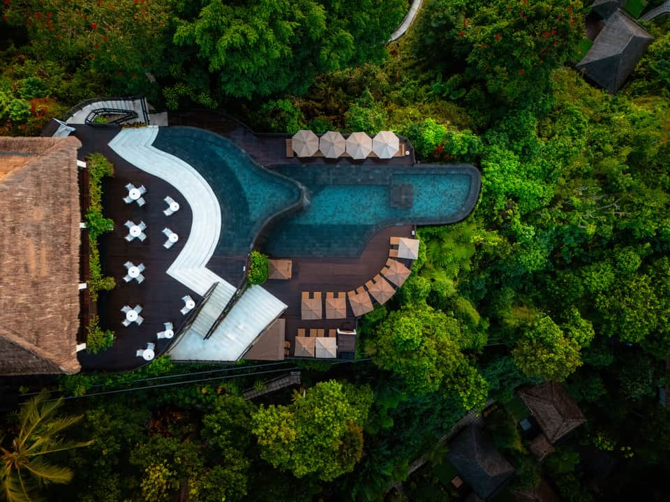 Overhead view of resort pools and spa area nestled within lush green forest landscape