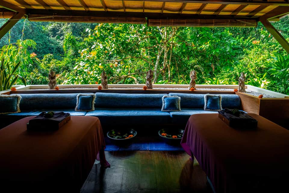 Covered spa area with blue cushioned seating overlooking terraced pools and tropical vegetation