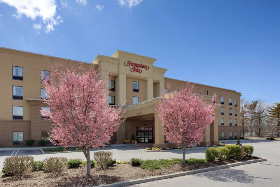 Hampton Inn exterior with blooming pink cherry blossom trees and main entrance with traditional signage