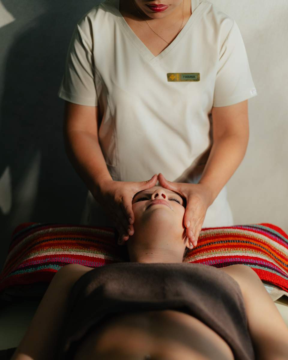 Spa therapist performing a facial massage on a client on a treatment table