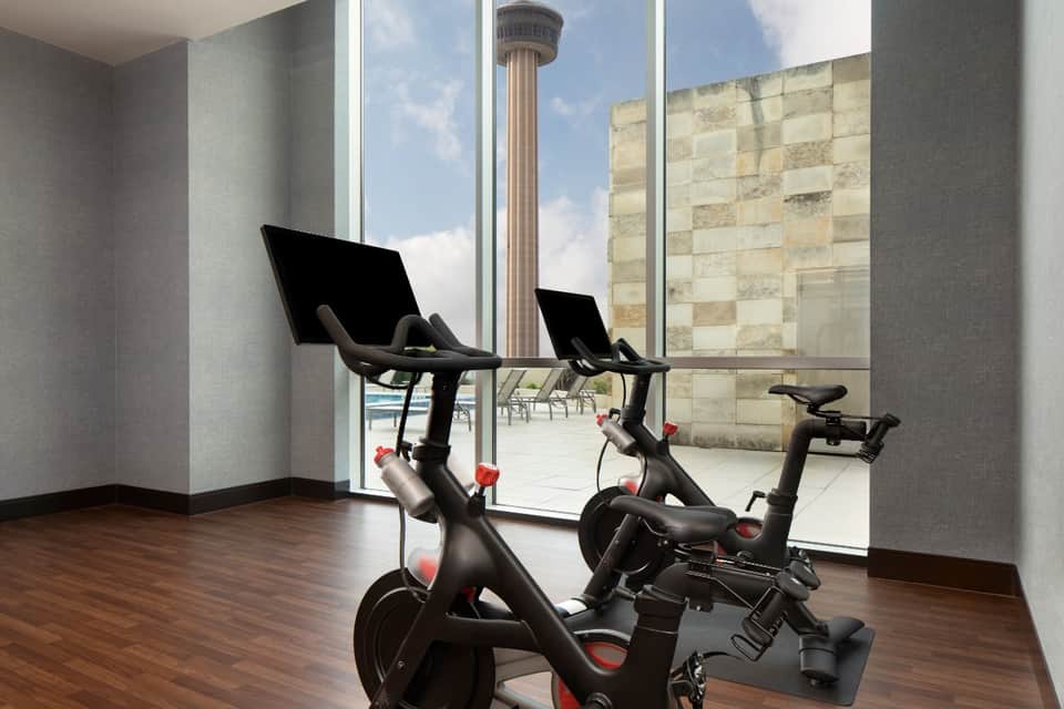 Modern fitness room with two stationary bikes overlooking city skyline and historic tower