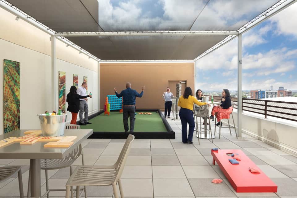 Modern rooftop terrace with games, seating, and city skyline view with retractable shade