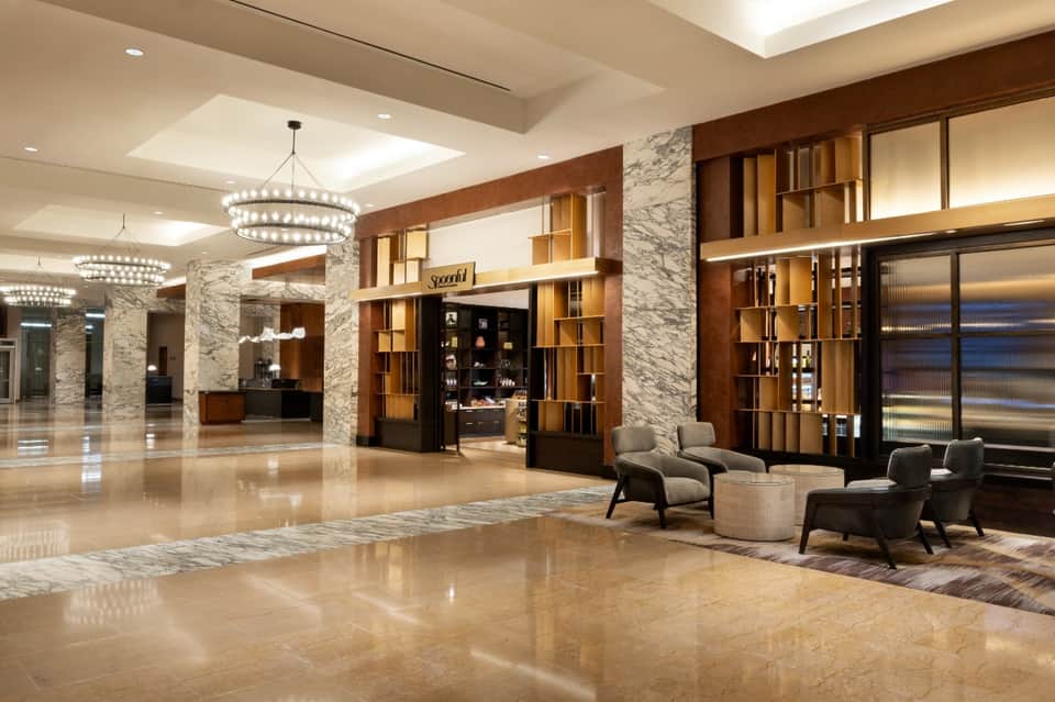 Elegant hotel lobby with marble columns, crystal chandeliers, and luxury retail displays