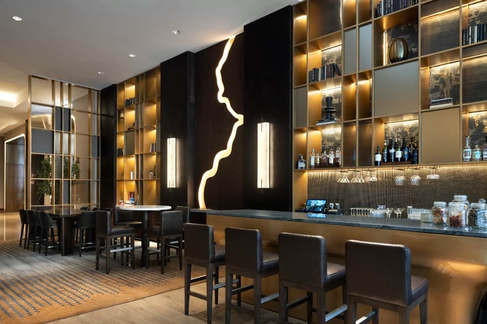 Upscale hotel bar with backlit shelving, neon lightning artwork, and ambient gold lighting at night