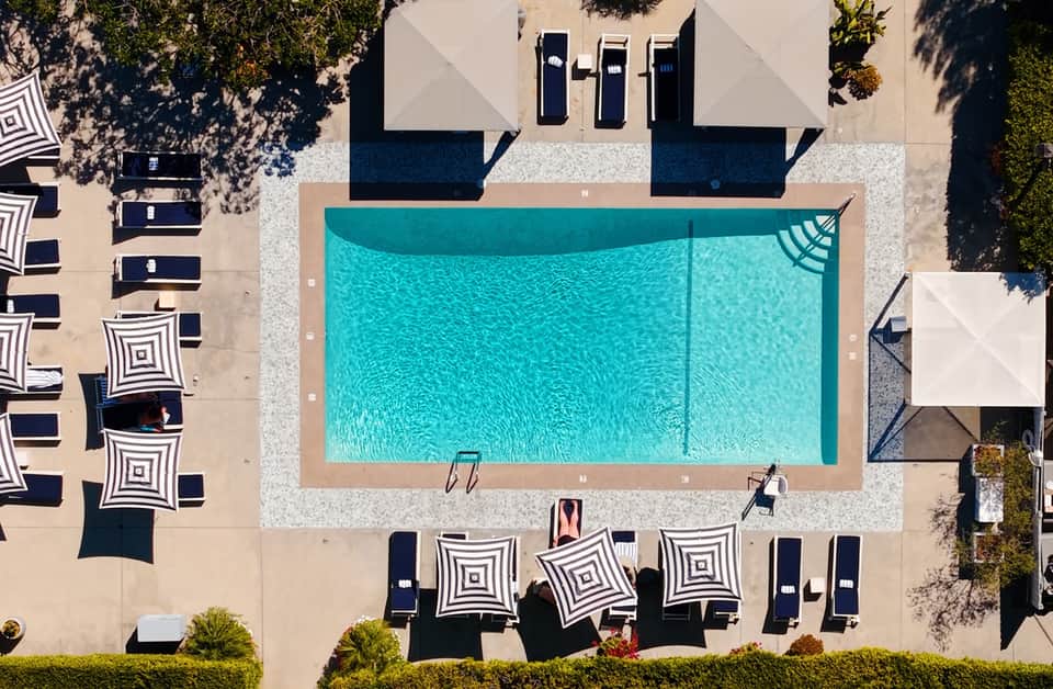 Aerial view of rectangular pool surrounded by striped umbrellas and loungers on a spacious resort deck