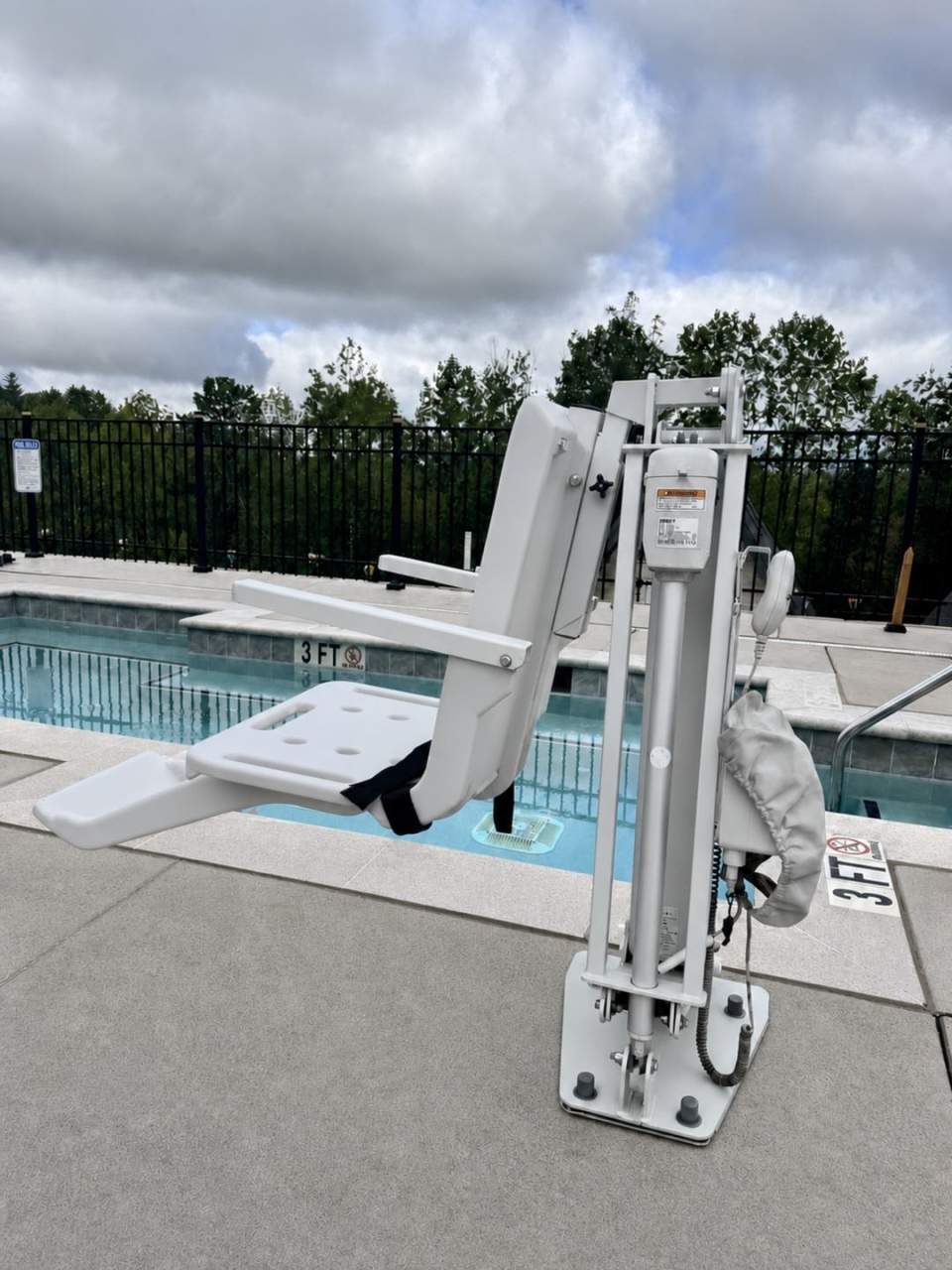 Accessible pool lift device at edge of indoor pool facility