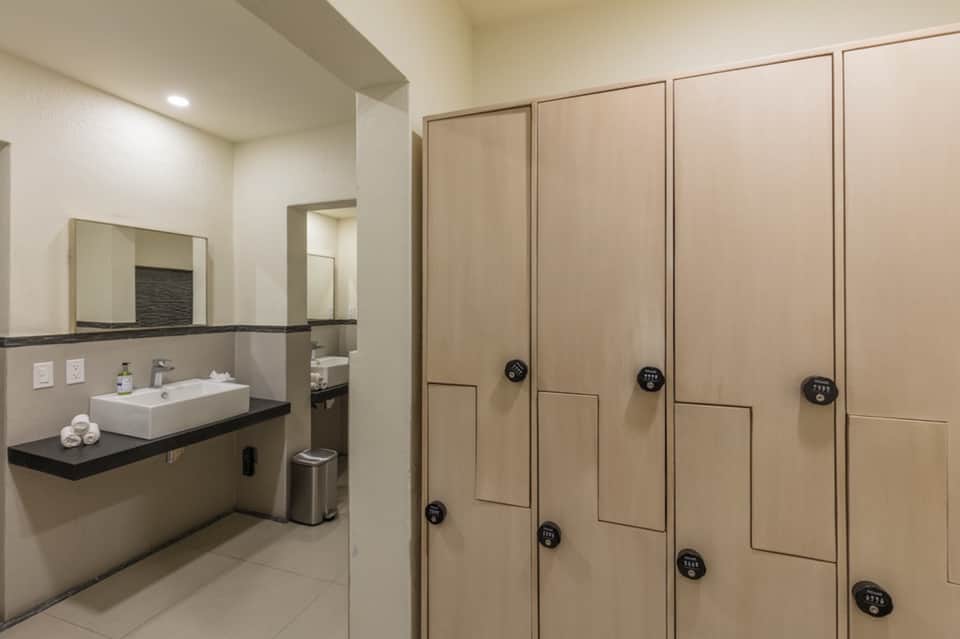Spa locker room with wooden lockers, white sink counter, and rolled towels in neutral tones