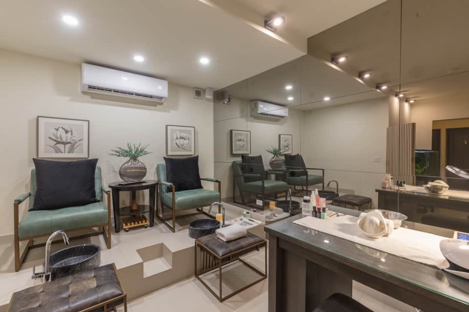 Modern spa lounge with teal armchairs, botanical artwork, treatment counter, and ambient lighting