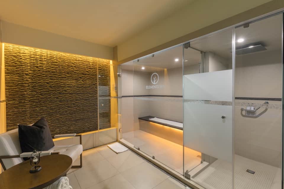 Luxury steam shower room with textured stone walls, golden accent lighting, and glass enclosure